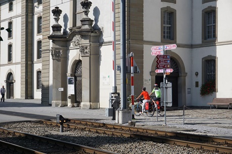 Radler passieren einen vor dem Rorschacher Kornhaus aufgestellten Wegweiser., der zeigt, dass sich hier verschiedene Nationale Schweizer Velorouten kreuzen.