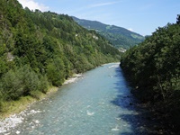 Der türkisgrüne, von sattgrünen Mischwäldern flankierte Rhein fließt auf Ilanz zu.